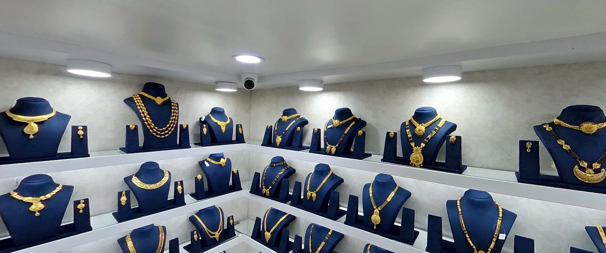 A jewellery store's gold-finish and mangalsutras wall: AD and silver sets on blue busts