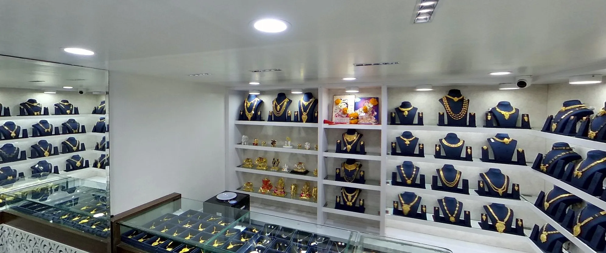 A jewellery store's pendant boxes: gold-finish sets on blue busts along white shelves, the pendant cases in front