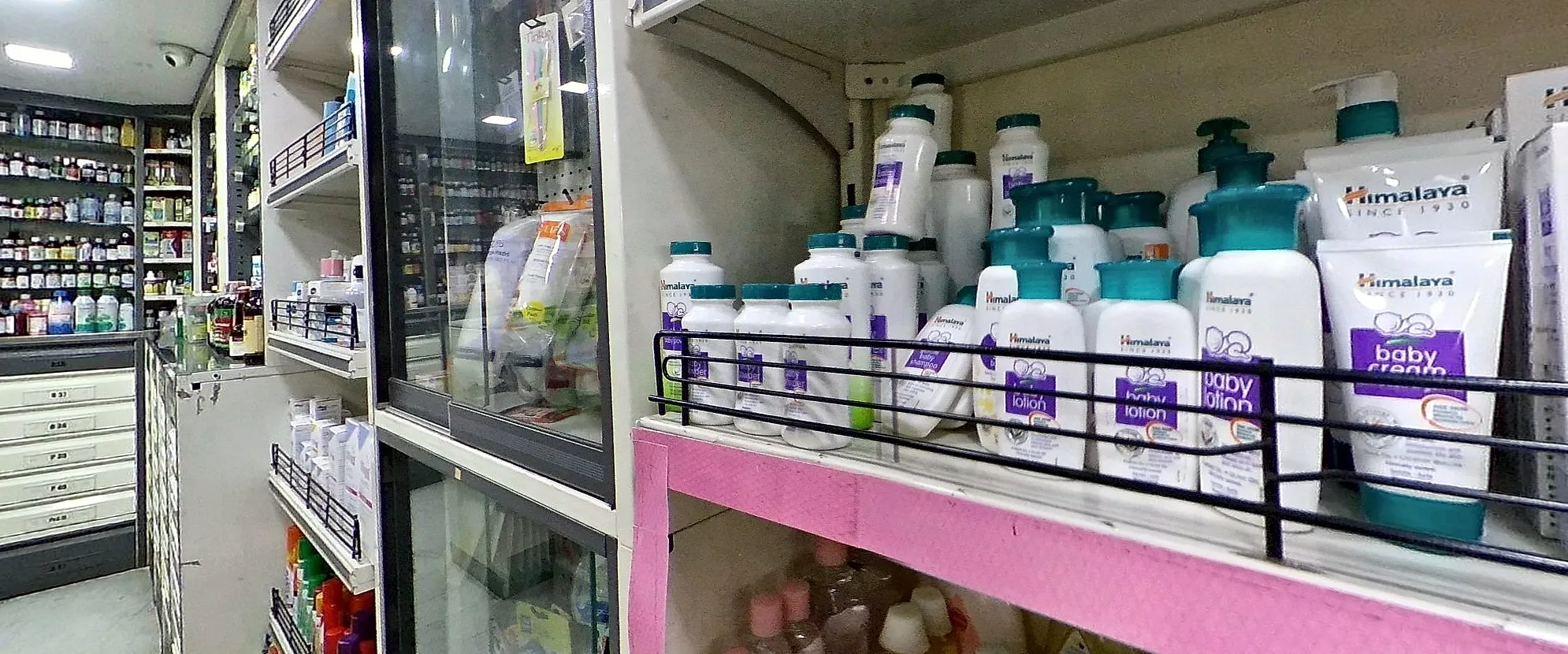 A pharmacy's baby-care shelf: shampoos, lotions and creams above a pink shelf strip